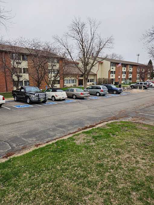 A parking lot with cars and a truck in front of a building.