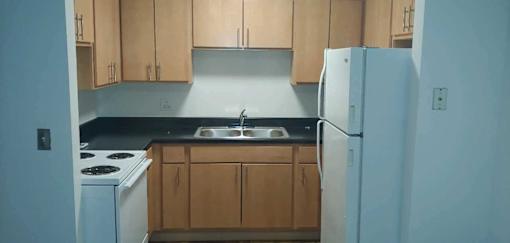 A kitchen with a white refrigerator and wooden cabinets.