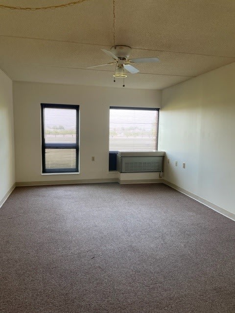 an empty room with a ceiling fan and two windows