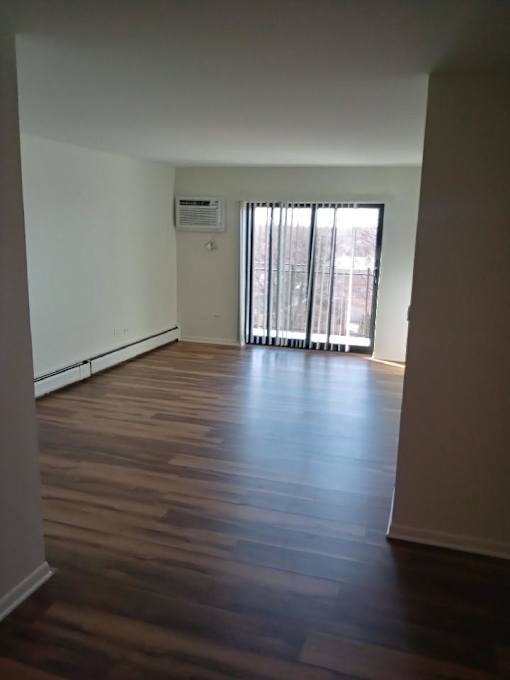 A room with wooden floors and a window with blinds.