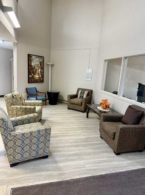 A living room with a painting on the wall and a sofa with a pillow on it.