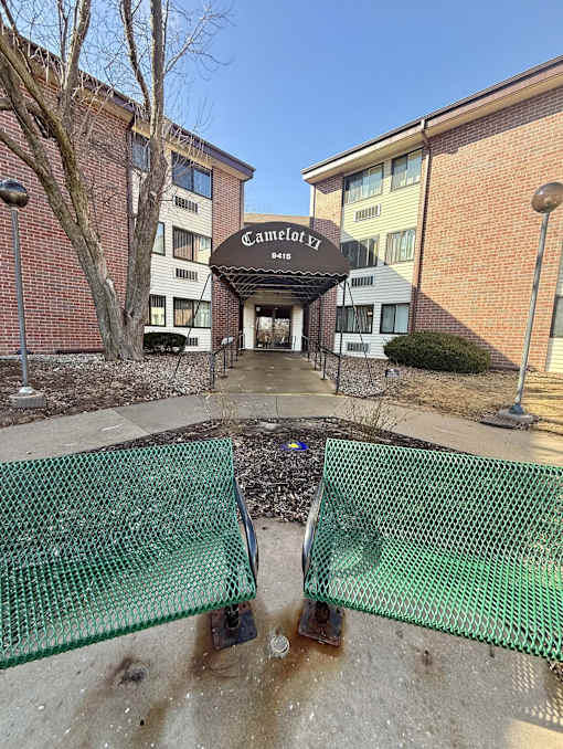 A green mesh fence is in front of a building with a sign that says "Camelot EZ".