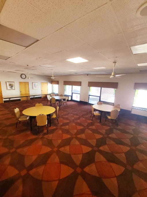 a large room with tables and chairs and a clock on the wall