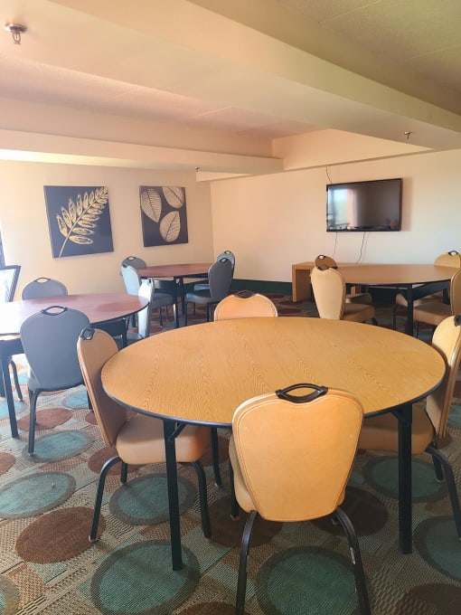 a room with a table and chairs and a television on the wall