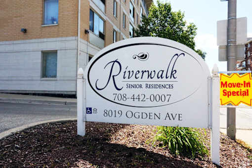 A sign for Riverwalk Senior Residences is displayed in front of a building.