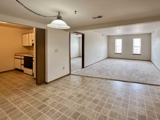 the living room and kitchen of an empty house with the door open