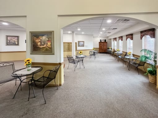 a dining room with tables and chairs and a large room with windows