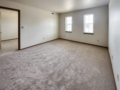 the living room of a home with carpet and a door to a bedroom