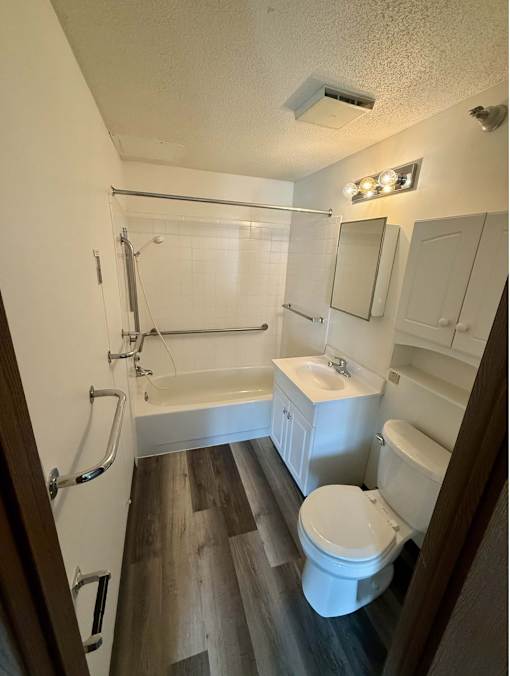 A white toilet is in a bathroom with a white sink and a white bathtub.