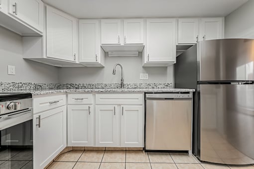 A kitchen with white cabinets and a stainless steel refrigerator.