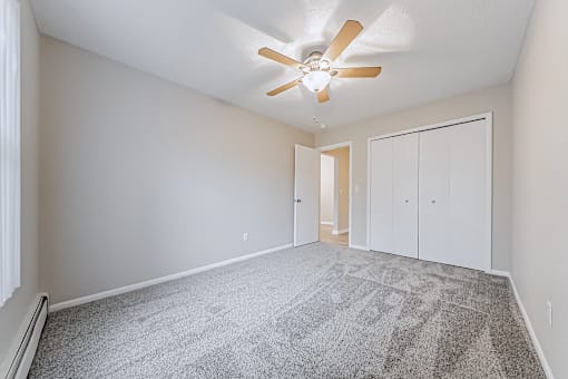 A room with a ceiling fan and carpeted floor.