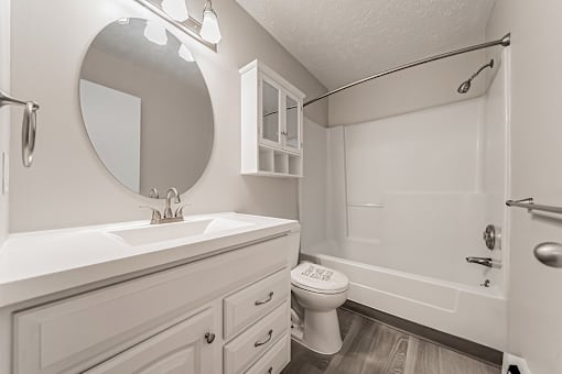 A white bathroom with a toilet, sink, and shower.