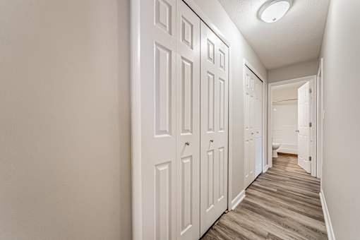 A hallway with white doors and wooden floors.