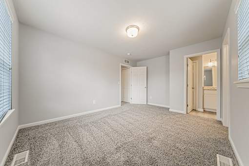 Townhome upstairs bedroom, carpeted, with attached bathroom.
