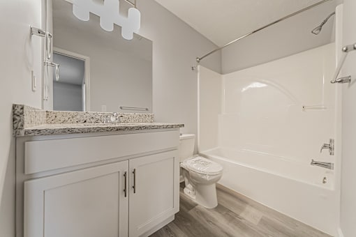 Updated townhome bathroom with granite countertop and white tub.