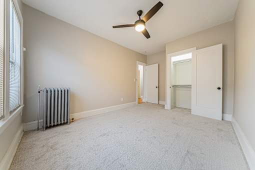 Carpeted bedroom with large closet and a ceiling fan.