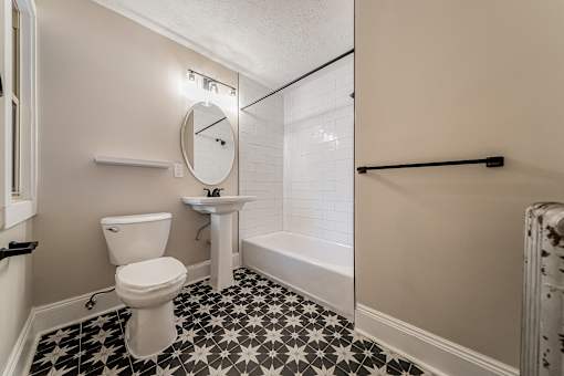 A bathroom with a toilet, sink, and a clock on the wall.