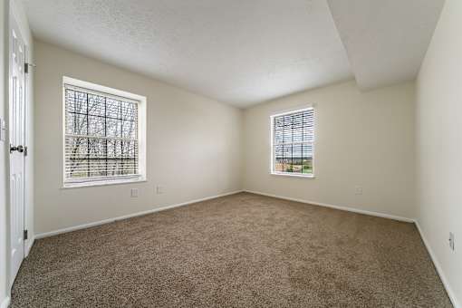 A room with carpeted floor and two windows. at Hunt Club Apartments, Apartments, Copley, OH