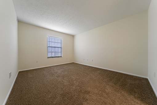 A room with a carpeted floor and a window with blinds at Hunt Club Apartments, Apartments, Copley, OH