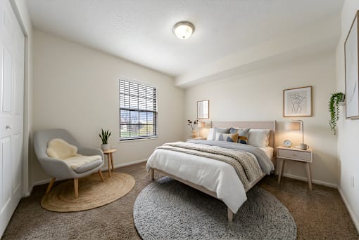 A bedroom with a bed, chair, and two lamps at Hunt Club Apartments, Copley, 44321
