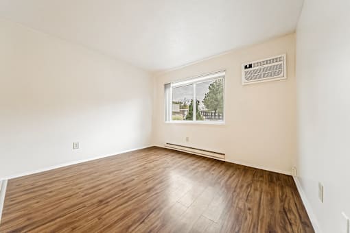 A room with a window and a wooden floor.