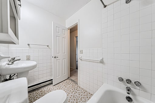 A white bathroom with a toilet, sink, and bathtub.