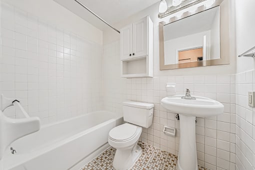 A white bathroom with a toilet, sink, and bathtub.