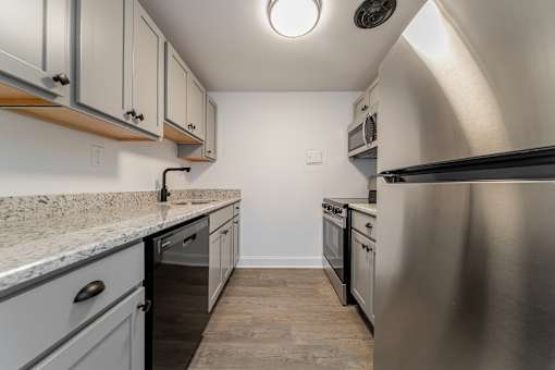 A kitchen with a stainless steel refrigerator and a marble countertop.