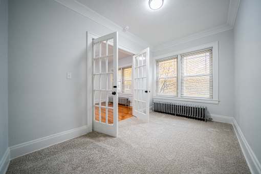A room with a white door and a window with a radiator under the window.at Integrity Cleveland Heights Apartments, Cleveland Heights, OH