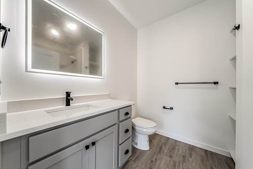 A bathroom with a white toilet and a sink with a mirror above it at Westwood Meadows, Westlake, OH, 44145