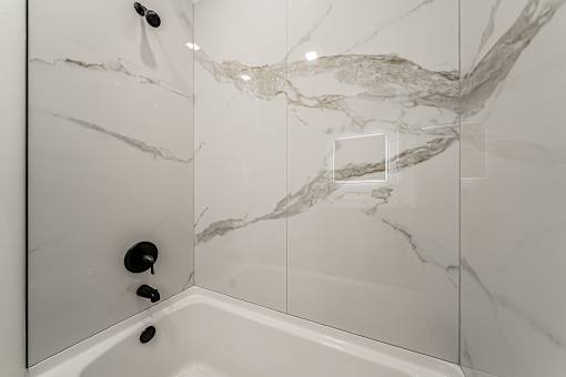 A white bathroom with a marble patterned shower at Westwood Meadows, Westlake, OH, 44145