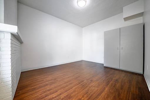 A bedroom with wooden floors and white walls.