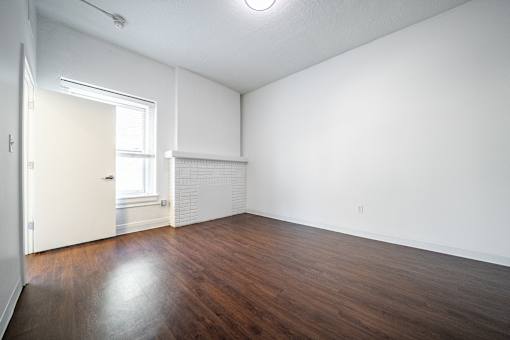 A bedroom with wooden floors and white walls.