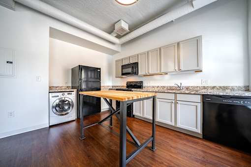 A kitchen with black appliances and wooden floors.