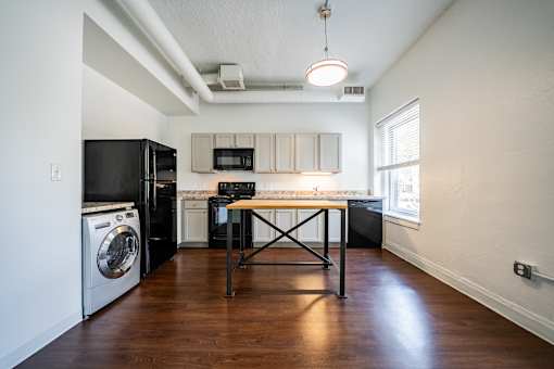 A kitchen with a black fridge and a black table.