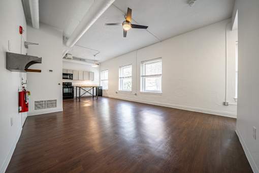 A large living room with a ceiling fan and wooden flooring.