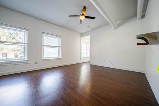 A room with a ceiling fan and wooden flooring.