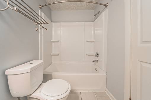 A white toilet sits next to a white bathtub in a bathroom. at Integrity Berea Apartments, Berea, 44017