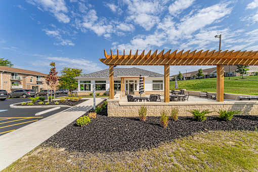 A wooden pergola is situated in the middle of a landscaped area.