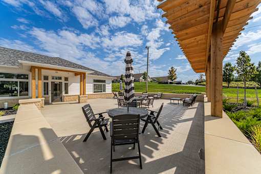 A patio with a table and chairs is shaded by a wooden pergola..