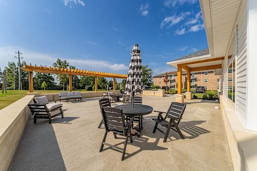 A patio with a table and chairs and a striped umbrella..