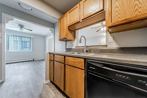 A kitchen with wooden cabinets and a black dishwasher at Integrity Chardon Apartments, Chardon,  Ohio