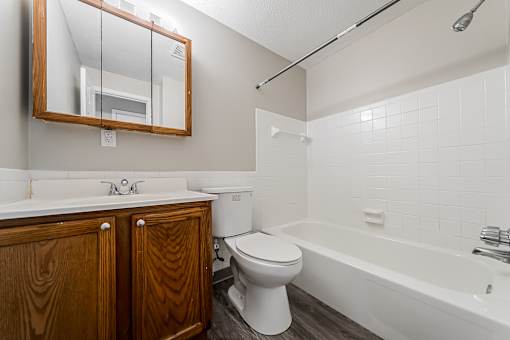 Bathroom with white tub and wood cabinet at Integrity Chardon Apartments, OH, 44024