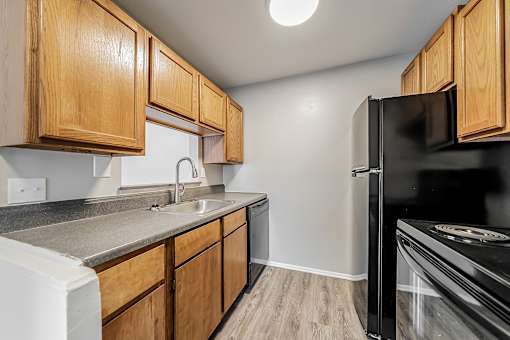 A kitchen with wooden cabinets and a black refrigerator at Integrity Chardon Apartments,Ohio