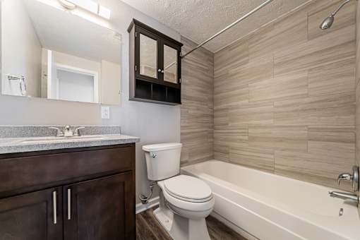 A bathroom with a white toilet, a sink, and a bathtub at Integrity Chardon Apartments, Chardon