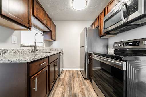 A kitchen with dark wood cabinets and stainless steel appliances at Integrity Chardon Apartments, OH, 44024