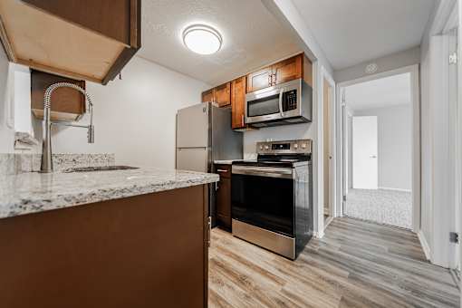 A kitchen with a granite countertop and wooden cabinets at Integrity Chardon Apartments,Ohio, 44024
