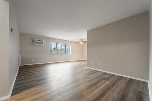 A room with wooden flooring and a window with blinds.