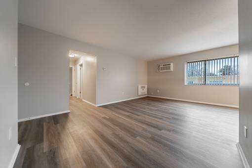 A room with wooden flooring and a window with blinds.