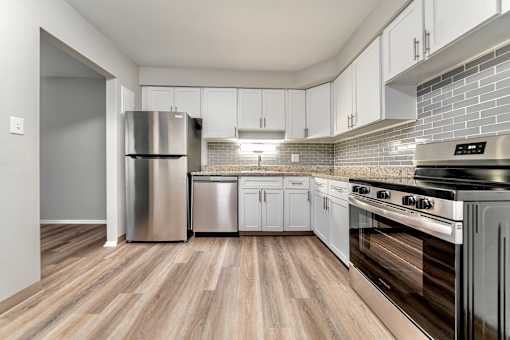 A kitchen with a stainless steel refrigerator, dishwasher, and oven.
